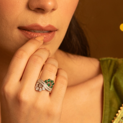 Woman wearing a green outfit and a silver ring with green stones.