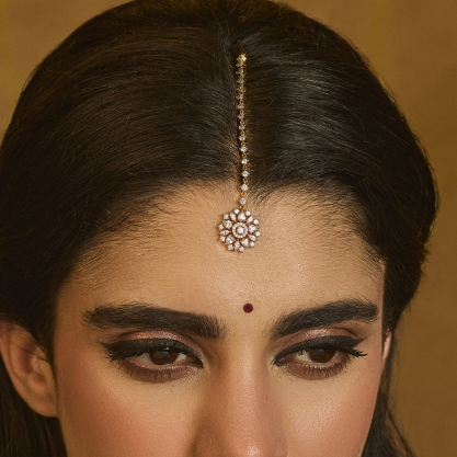 Woman wearing a traditional maang tikka and bindi.