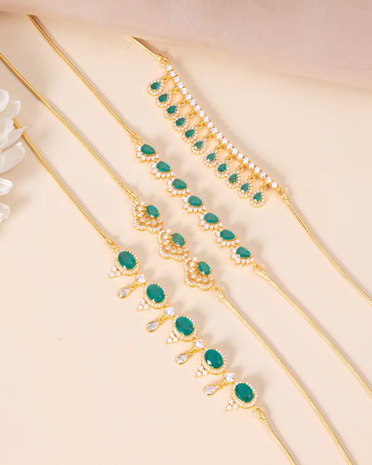 Elegant gold-plated necklace and bracelet set with green stones and pearl accents on a beige background.