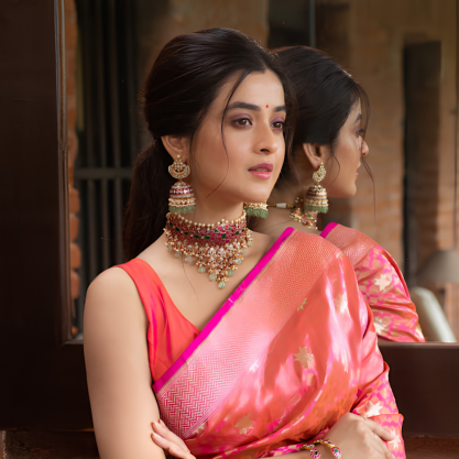 Woman wearing a pink saree with a traditional gold choker necklace, jhumka earrings, and bangles