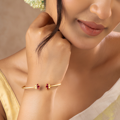 Woman wearing a gold floral bracelet with red gemstones