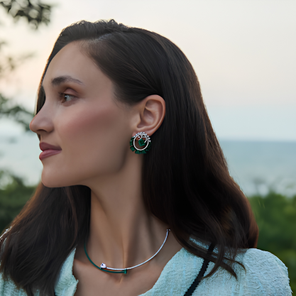 Woman wearing emerald green stud earrings with a silver necklace