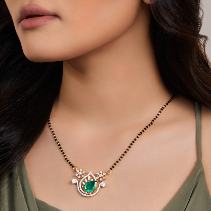 Woman wearing a delicate silver mangalsutra with a green gemstone pendant.