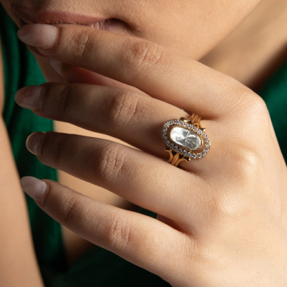 Silver statement ring worn on a woman's hand with an intricate oval design.