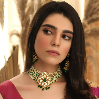 A woman wearing a traditional silver choker necklace with green gemstone detailing and matching earrings.