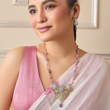 Woman wearing a pink saree and colourful silver necklace.
